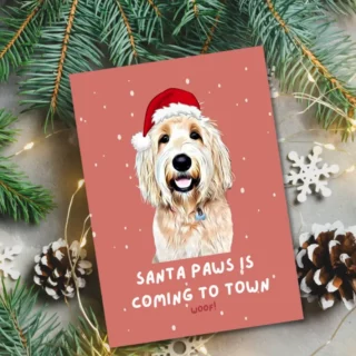 Customizable Christmas card featuring a smiling golden retriever with a Santa hat, titled 'Santa Paws is Coming to Town', amidst holiday decor.