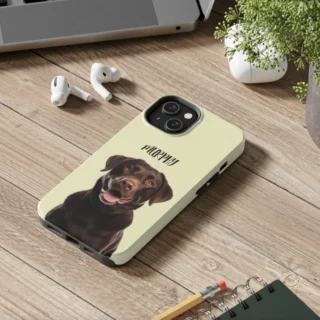 Custom phone case with 'Murphy' the chocolate Labrador's portrait on a wooden desk.