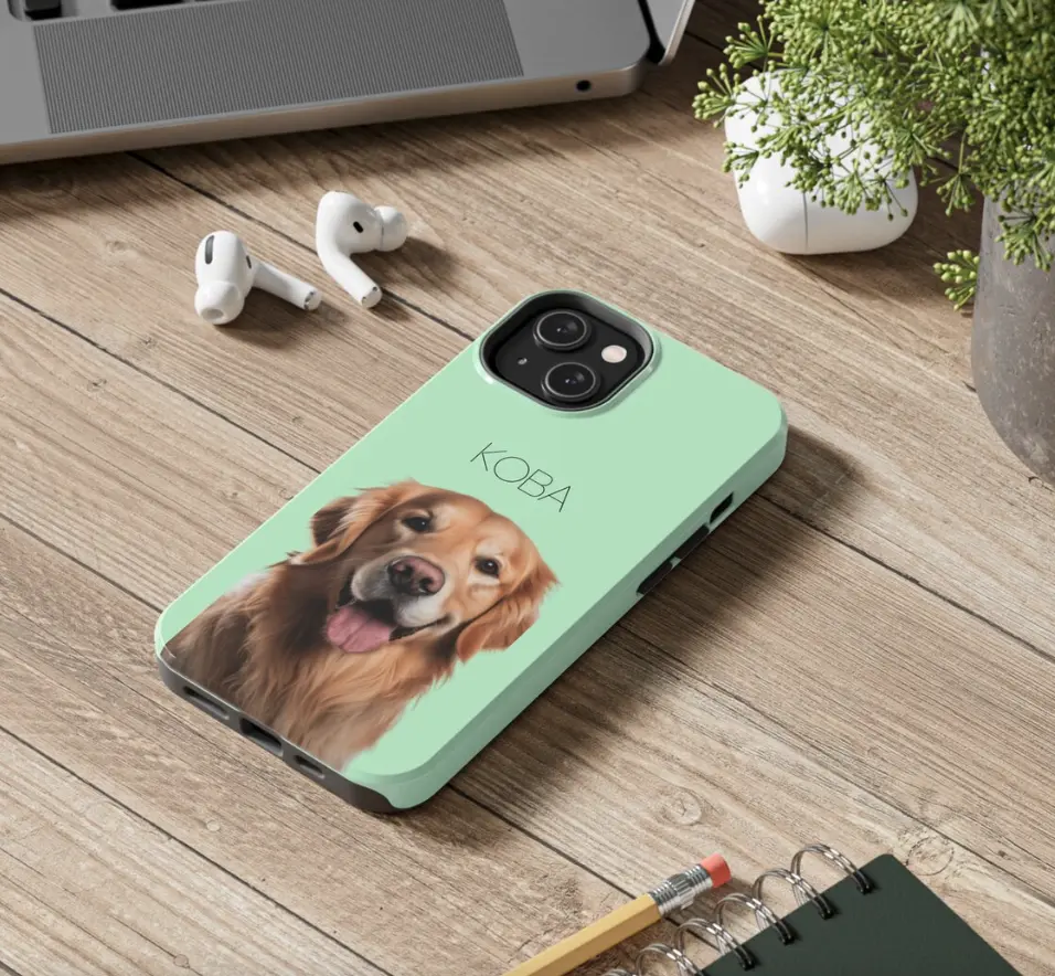 Green phone case featuring 'Koba' the Golden Retriever's smiling face on a work desk.